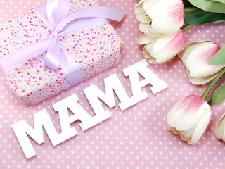 bunch of flowers with a gift box and word mama on pink polka dot background