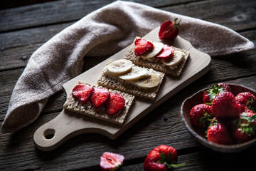 Fruity toast on wooden background. Strawberries, bread, butter and cheese.Vintage style