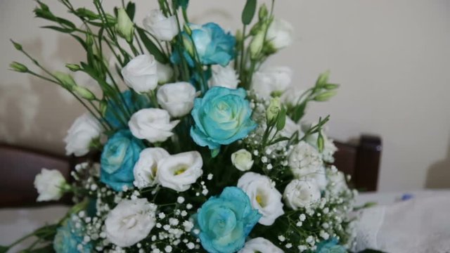 Fiori azzurri e bianchi disposti su un tavolo per un battesimo.