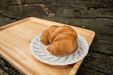 Croissant baked on wooden plate with copy space.