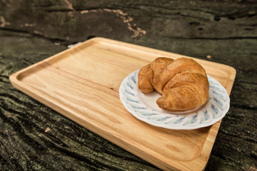 Croissant baked on wooden plate with copy space.