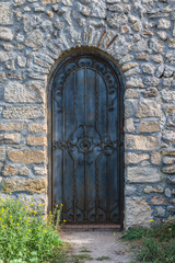 Fototapeta na wymiar Heavy closed door on a stone wall of medieval fortress, made riveted wood
