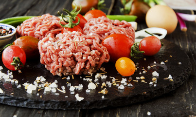 raw minced meat, vegetables with salt and spices, selective focus