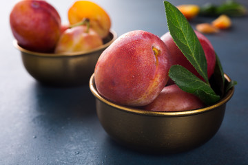 Fresh plums in bronze bowl on blue stone background. Selective focus. Healthy food concept. Copy space.