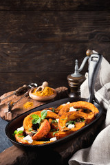 Roasted, baked pumpkin with addition aromatic herbs, goat cheese and mint. Healthy food concept with copy space.