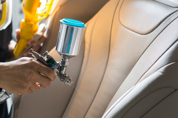 Car detailing series : Closeup of hand coating beige luxury car seat