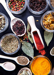 Spices on black background in special jars. Food