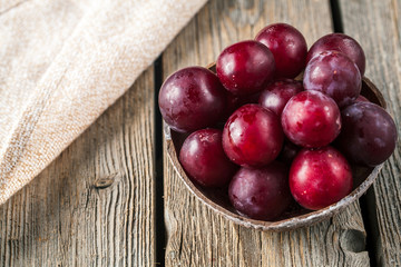 Old plate with plums over dark board. Top view. Fruits background with space for text. Agriculture, Gardening, Harvest Concept.