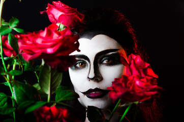 Halloween. Beautiful face-art girl and red roses