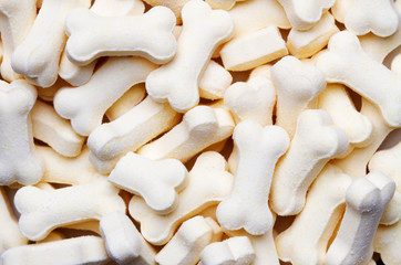 Pile of white color dog biscuits in the shape of a bone for a pet food background
