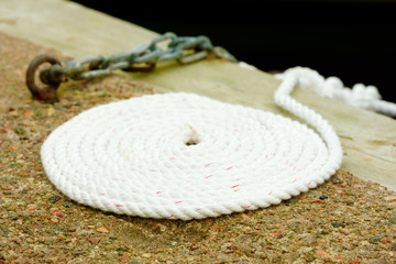 Coiled white rope on stone and wood pier.