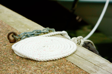 Coiled white rope on stone and wood pier.