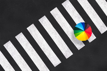 Top view of a rainbow umbrella on a pedestrian crosswalk, urban photo