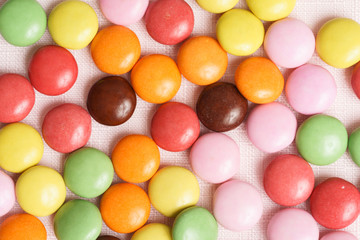 Colorful chocolate buttons on pink background 