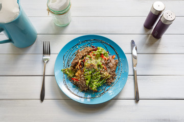Restaurant food on wooden table. Warm meat salad with sesame
