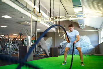 Man with battle rope in functional training fitness gym