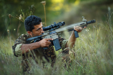 Man of Arab nationality in camouflage with a gun aiming at a tar