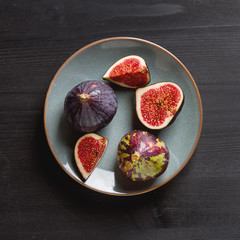 Juicy ripe figs on a plate. Dark wooden background. Top view