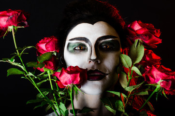 Halloween. Beautiful face-art girl and red roses
