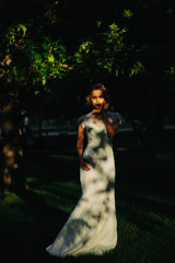 Trees' shadows lie over a stunning lady in long white dress