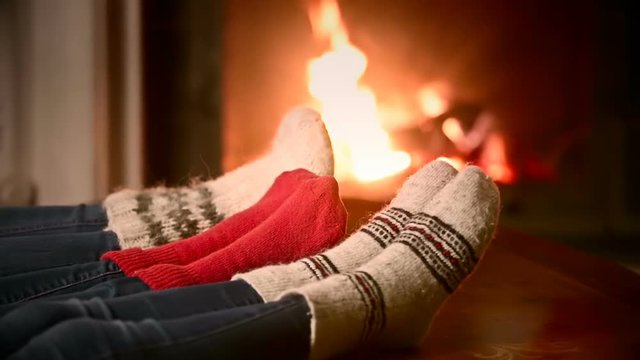 Closeup shot of mother, father and a child in woolen socks warming at the fireplace
