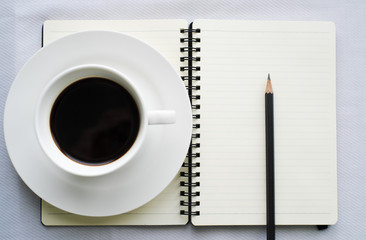 Coffee in white cup with Journal book and pencil