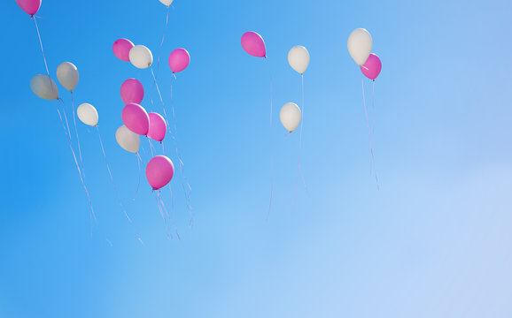 Pink and white balloons flying in the sky