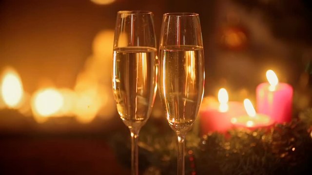 Two glasses of champagne on table in front of burning fireplace at Christmas eve.