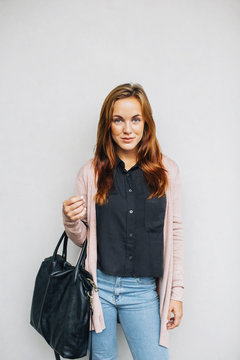 Portrait of smiling young woman with black leather bag