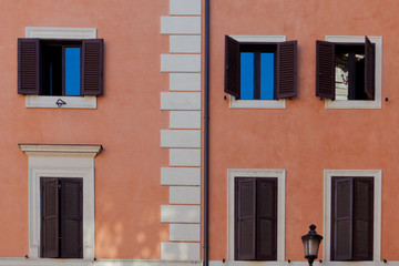 Obraz premium Peach building with windows hidden behind dark brown shutters