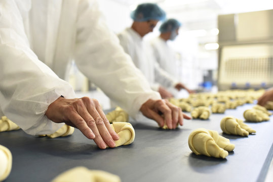 Workers at production line in a baking factory with croissants