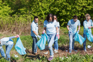 Naklejka na ściany i meble volunteers with garbage bags cleaning park area