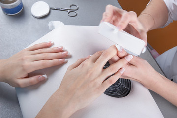 Manicure. Processing of extended nails by a whetstone