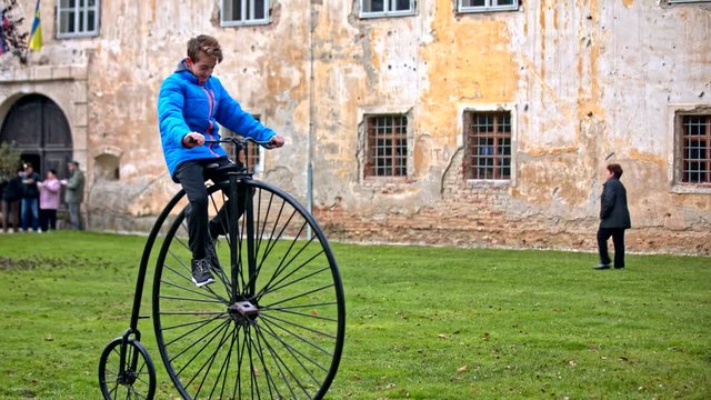 Boy waving from penny-farthing bicycle
