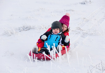 Fototapeta na wymiar Two children sledding in winter