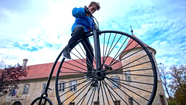 Boy climb to penny-farthing bicycle statue