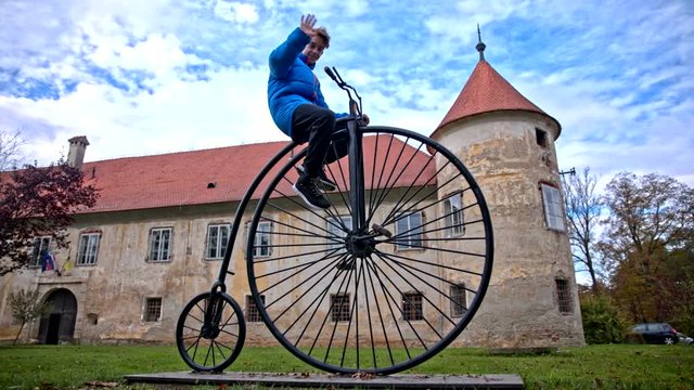 Boy waving from historical penny-farthing bicycle