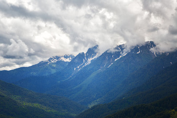 Fototapeta na wymiar Big clouds over the snow-capped mountain peaks