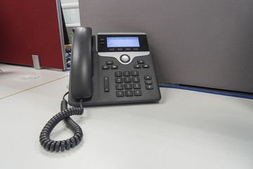IP phone on white desk and gray partition at office