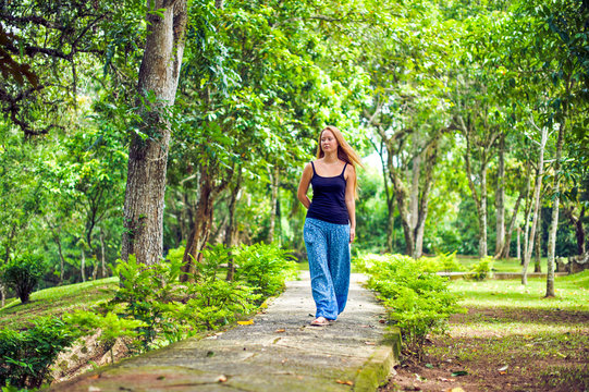 The girl walks in a tropical garden