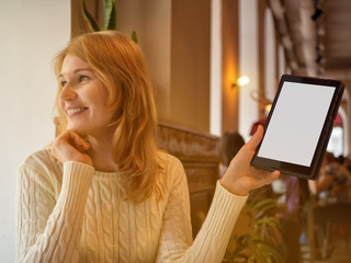 Attractive woman with beautiful smile watching good news on mobile phone during rest in coffee shop. Caucasian girl shows the screen of the tablet. Concept leisure , relaxing, free time in cafe.