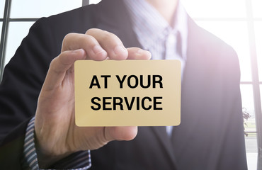 businessman hand holding a business card with a message 'at your service' for business advertise concept.