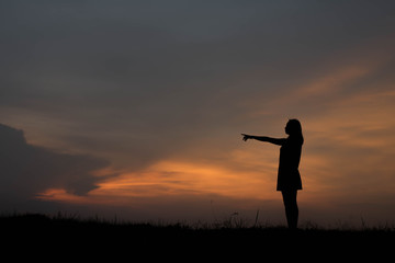 silhouette young woman pointing forward to Dream ahead in sunset