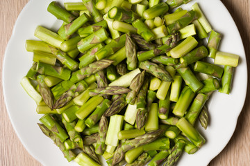 Close up on sliced pieces of green asparagus on a white plate