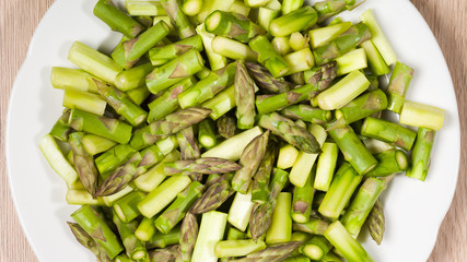 Close up on sliced pieces of green asparagus on a white plate