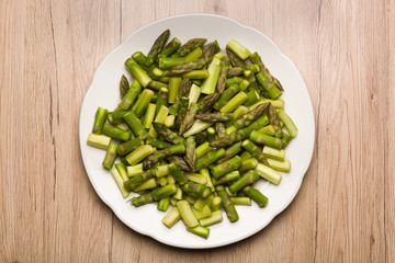 Close up on sliced pieces of green asparagus on a white plate