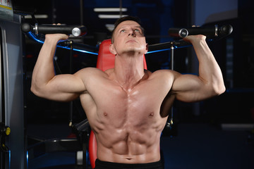 Fototapeta na wymiar Handsome athletic fitness man posing and trains in the gym.