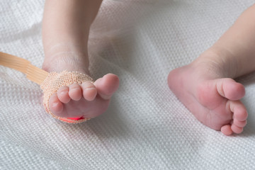 Pulse oximeter sensor on the feet of newborn baby in a hospital bed close-up