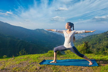 Woman doing yoga asana Virabhadrasana 2 - Warrior pose outdoors