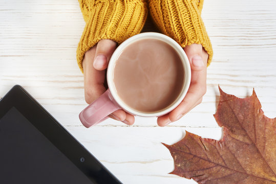 Cocoa cup and woman hand, autumn leaves, tablet pc